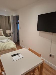 a room with a table and a tv on a wall at The Greenwood Guest Room in Brimsdown Station