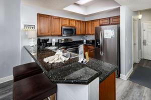 uma cozinha com armários de madeira e uma geladeira de aço inoxidável em Ariel Dunes I 507 Beach side resort em Destin