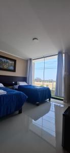 a bedroom with two beds and a large window at Hotel Nueva Vista Huarmey in Huarmey