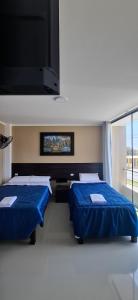 a room with two beds and a flat screen tv at Hotel Nueva Vista Huarmey in Huarmey