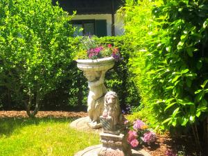 una statua di pietra con fiori in un giardino di Apartment SEEnsucht - Tolle Lage, nah am See, perfekt für Familien a Schliersee