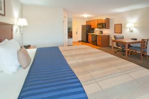 a bedroom with a large bed with a blue blanket on it at Candlewood Suites Roswell by IHG in Roswell