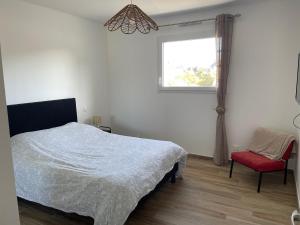 a bedroom with a bed and a window and a red chair at Chez Tristan in Plouguerneau