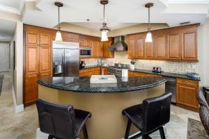 a kitchen with a large island with black counter chairs at Bella Riva 301 Large Gulf Front condo in Fort Walton Beach
