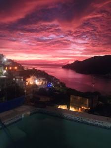 een uitzicht op de oceaan bij zonsondergang vanaf een zwembad bij Artists loft w panoramic views pool in Taganga