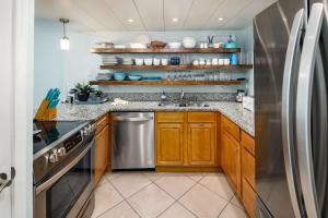 a kitchen with wooden cabinets and a stainless steel refrigerator at Emerald Isle 610 Beach Front condo in Fort Walton Beach