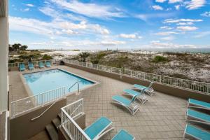 a balcony with a swimming pool and chairs and the beach at Gulf Dunes 106 Gulf Front condo in Fort Walton Beach