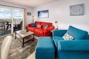 a living room with a red couch and blue chairs at Gulf Dunes 106 Gulf Front condo in Fort Walton Beach