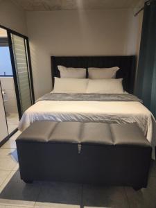 a large bed with a black headboard and a bench at The white house in Midrand +9 photos