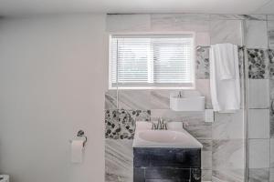 a white bathroom with a sink and a window at Tiny Home with a Huge View in Ruidoso