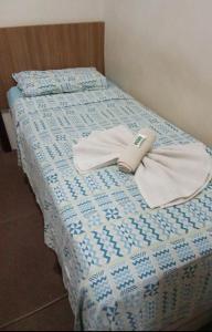 a bed with a blue and white comforter and towels at Hotel Pousada Accordes in Campo Grande