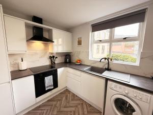 a kitchen with white cabinets and a dishwasher at 2 Bedroom City Centre Apartment By Travel Lets Short Term Rental Agency Derry With Free WiFi in Derry Londonderry
