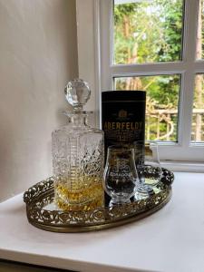 Cosy cottage for two in the highlands في Fortingall: زجاجة من الويسكي وكأسين على صينية