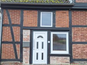 a brick building with a white door and two windows at Charmante Fachwerkhaushälfte mit Sauna in Rosche