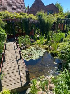 a garden with a wooden bridge over a pond at Charmante Fachwerkhaushälfte mit Sauna in Rosche