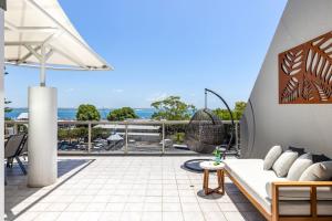 a balcony with a couch and a view of the ocean at Nelson Towers- Overlooking The Bay in Nelson Bay