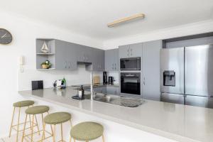 a kitchen with a counter with stools and a refrigerator at Nelson Towers- Overlooking The Bay in Nelson Bay