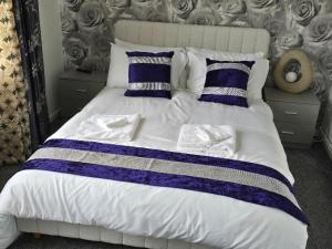a large bed with blue and white sheets and pillows at Hornchurch Cozy 2-Bed Flat with Street Parking in Hornchurch