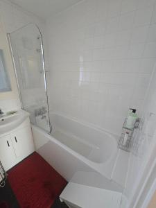 a white bathroom with a tub and a sink at Hornchurch Cozy 2-Bed Flat with Street Parking in Hornchurch