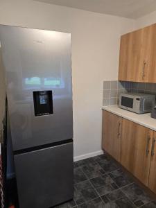 a kitchen with a refrigerator and a microwave at Hornchurch Cozy 2-Bed Flat with Street Parking in Hornchurch +11 photos