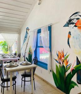a dining room with tables and birds painted on the wall at Pousada dos Pássaros Geribá in Búzios +45 photos