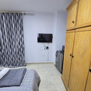 a bedroom with a bed and a dresser and a tv at Cozy Private Studio DBL in ‘Ezbet `Abd el-Ḥamîd