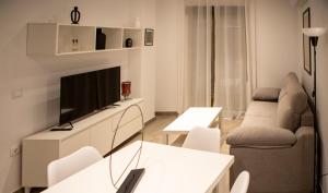 una sala de estar con televisión y un sofá en Apartamentos Palma del Río CAROLA, en Linares