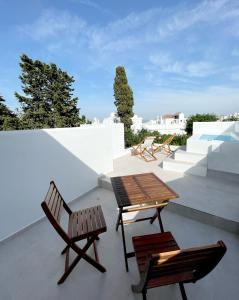 a patio with two chairs and a wooden table and chairs at Hotel Boutique Maram - Adults Only in Vejer de la Frontera
