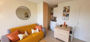 Una sala de estar con un sofá amarillo y una cocina. en Appartement Port Santa Lucia, en Saint-Raphaël
