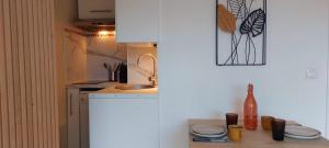 Una cocina con un fregadero y una encimera con tazas y una botella. en Appartement Port Santa Lucia, en Saint-Raphaël