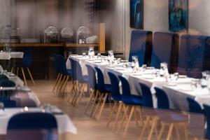 a row of tables with blue chairs and white tablesearcher at Landhotel in Hella +129 photos