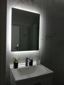 ein Badezimmer mit einem weißen Waschbecken mit Spiegel in der Unterkunft Xeni Deluxe 1 in Prizren + 13 Fotos