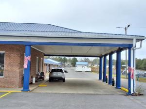 un parcheggio con un'auto parcheggiata sotto un garage di Travelodge by Wyndham-Thomasville AL a Thomasville