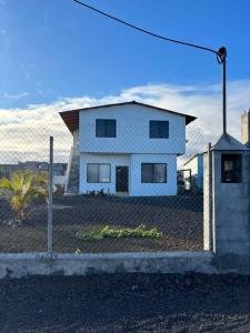 a white house behind a chain link fence at La casa de Luisa in Puerto Villamil