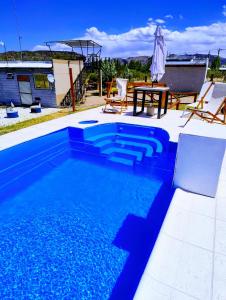 una piscina azul con mesa y sillas en Preciosa Casa con Terraza al Valle Grande, San Rafael Mendoza de 1 a 5 Personas, en Valle Grande