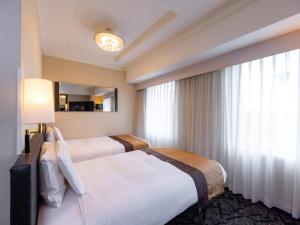 a hotel room with two beds and a mirror at APA Hotel Nihonbashi Hamacho Ekiminami in Tokyo