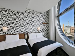 two beds in a room with a window at APA Hotel Nihonbashi Hamacho Ekiminami in Tokyo