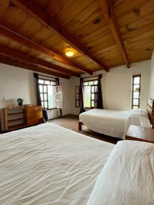 Dos camas en un dormitorio con techos y ventanas de madera. en Cabañas Las Camelias, en Cuetzalán del Progreso