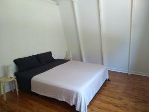 a bedroom with a white bed and a wooden floor at Iluka Rainforest Beach Shack Eco-Home in Woombah +8 photos