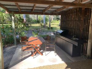 a patio with a table and chairs under a pergola at Iluka Rainforest Beach Shack Eco-Home in Woombah