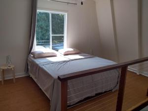 a small bed in a room with a window at Iluka Rainforest Beach Shack Eco-Home in Woombah