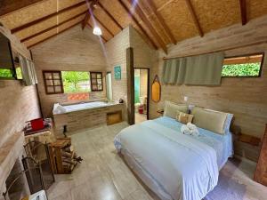 ein Schlafzimmer mit großem Bett und Badewanne in der Unterkunft Chalé na Montanha - Charme e Natureza in Santo Antônio do Pinhal