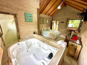 eine große Badewanne in einem Zimmer mit einem Bett in der Unterkunft Chalé na Montanha - Charme e Natureza in Santo Antônio do Pinhal + 19 Fotos