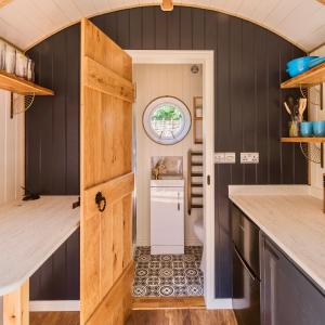 a tiny house with a door leading into a kitchen at The Shepherd's Hut at Hidden Wood Glamping in Corsley