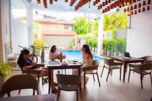 three women sitting at tables in a restaurant with a pool at Elements Hostel And Coworking in Weligama