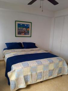 a bedroom with a bed with a blue comforter at Apartamento Isla de Margarita in Pampatar