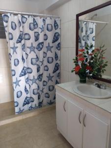a bathroom with a sink and a blue and white shower curtain at Apartamento Isla de Margarita in Pampatar