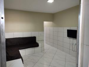 Un baño con azulejos blancos y un sofá negro. en Casa para temporada 2 Roberto, en Praia Grande
