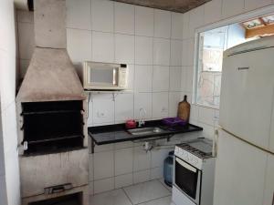 y cocina con fogones, horno y microondas. en Casa para temporada 2 Roberto, en Praia Grande