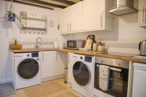 a kitchen with white cabinets and white washing machines at Little Thornsett in Buxton +8 photos